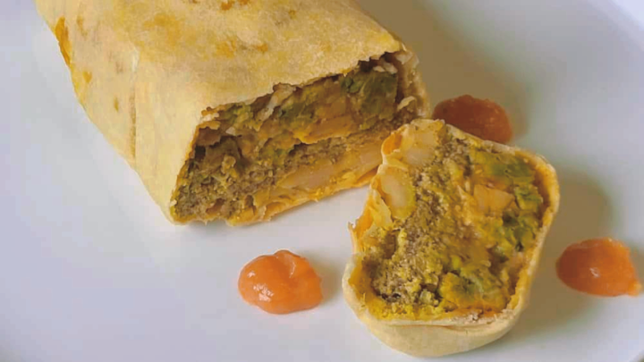 Un piatto gourmet vegetale a base di carta di riso ripiena di hummus di ceci e clorofilla di spinaci, servito con salse colorate.