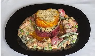 Un piatto gourmet vegano composto da strati di colori e ingredienti, con un contorno di verdure e una salsa cremosa, presentato elegantemente su un piatto nero.