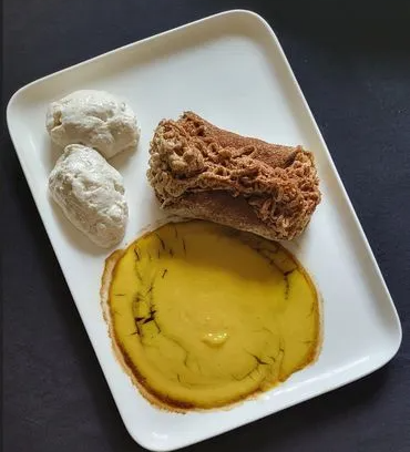 Un piatto di dessert composto da un cannolo a forma di taco ripieno di crema al caffè, servito con una riduzione al caffè e due palline di gelato al mascarpone.