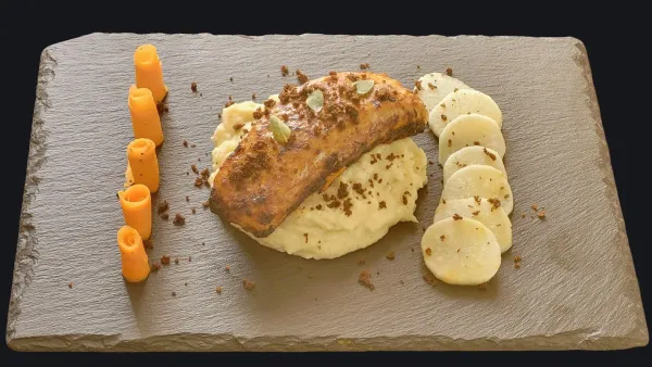 Piatto gourmet con filetti di carne su purè di patate, guarnito con croccante, fette di radice di verdura e carote a spirale.