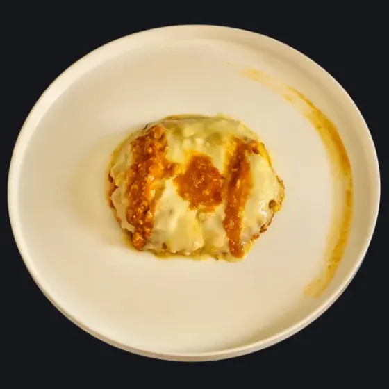 Piatto gourmet di lasagna vegana con ragù di tempeh e besciamella, servito su un piatto bianco.