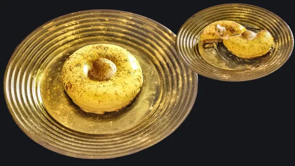 Donut al lime glassato su un piatto dorato, con una decorazione di spezie sopra e una porzione tagliata a lato.