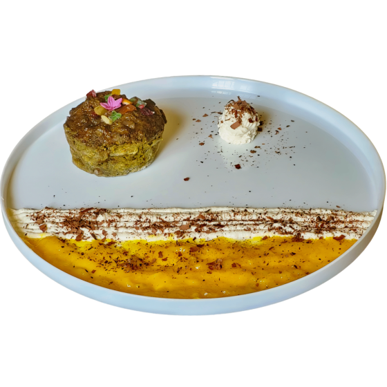A plated dessert featuring a cake topped with nuts and petals, accompanied by a dollop of whipped cream and a decorative line of chocolate and mango sauce.