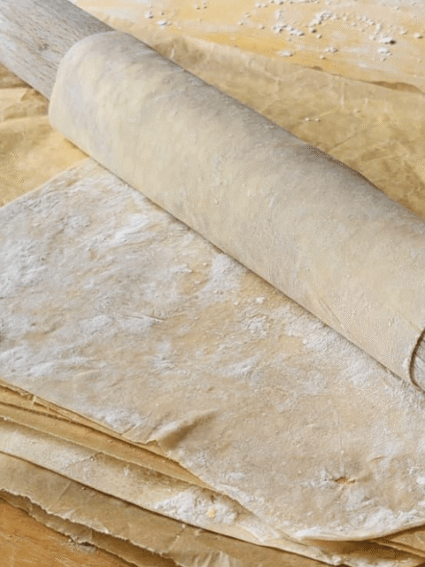 Mattarello con avvolta pasta fillo fatta in casa su tavolo marrone