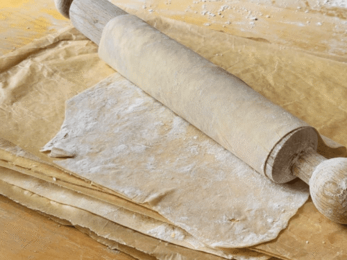 Mattarello con avvolta pasta fillo fatta in casa su tavolo marrone
