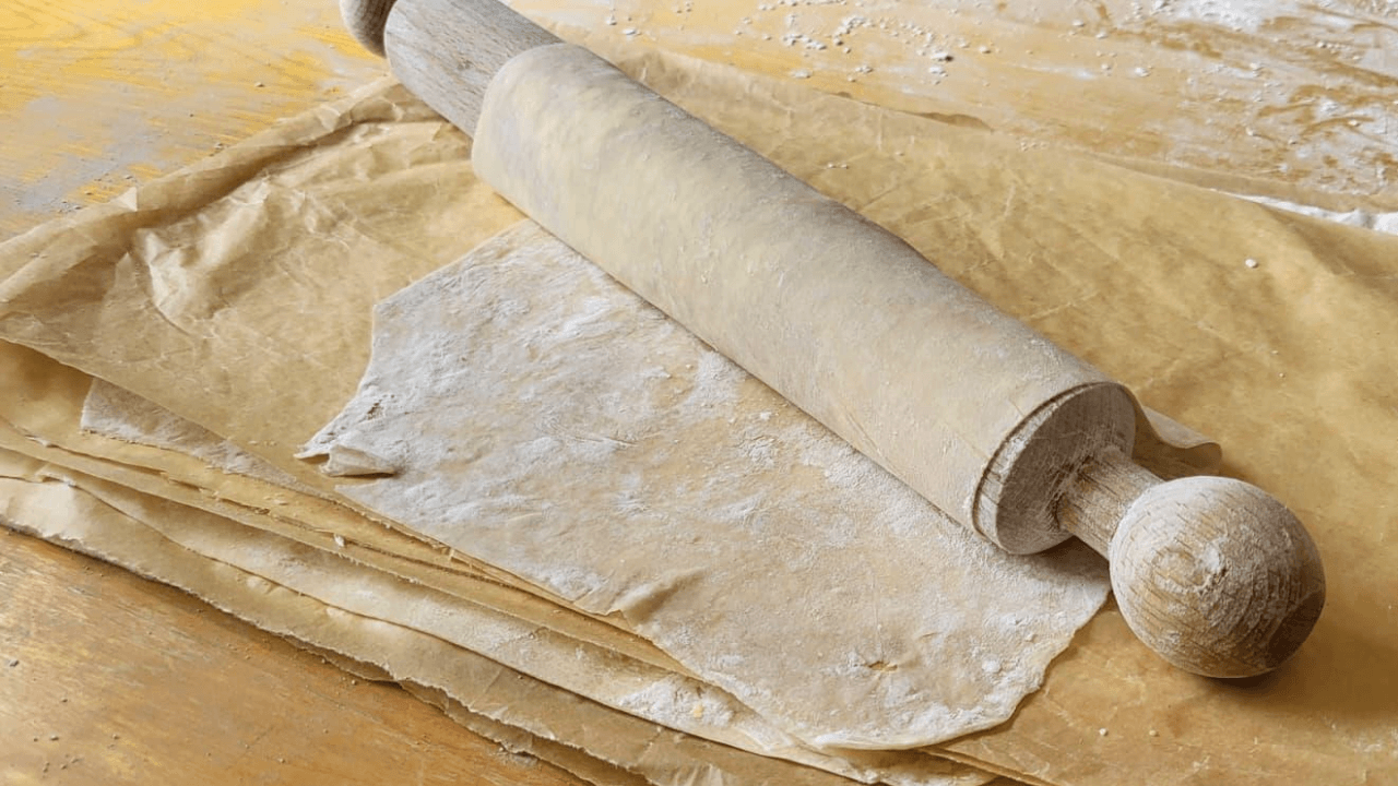 Mattarello con avvolta pasta fillo fatta in casa su tavolo marrone