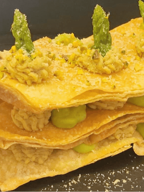 Sfoglie di pasta fillo intervallate da spuntoni di creme colorate su piatto nero ardesia