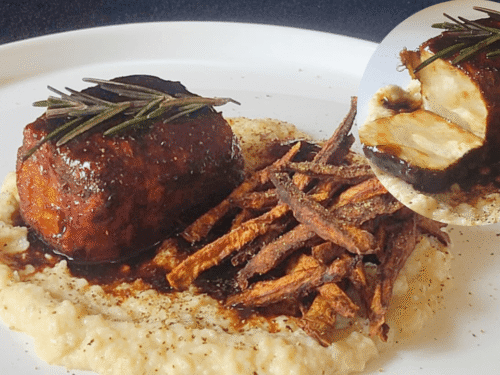Lingotto marrone di sedano rapa su una crema gialla e chips su piatto bianco