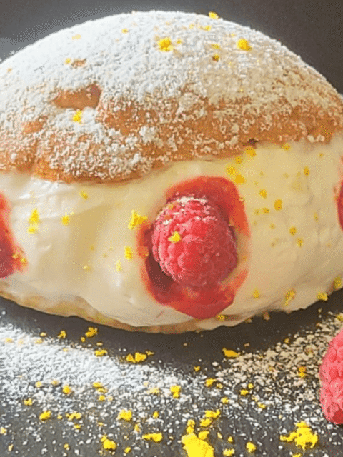 Maritozzo ripieno di panna e lamponi su piatto ardesia nero