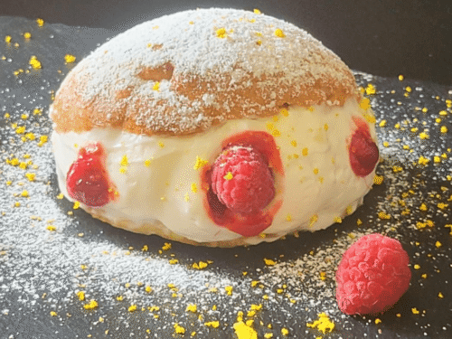 Maritozzo ripieno di panna e lamponi su piatto ardesia nero