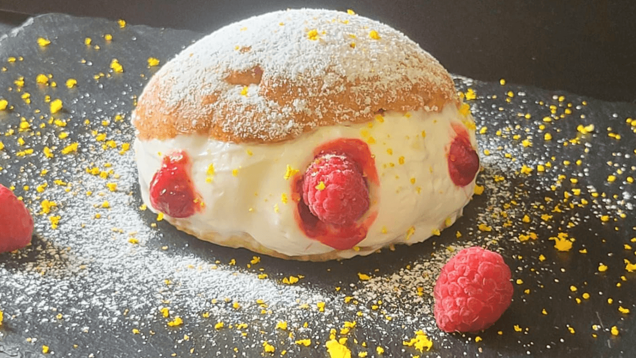 Maritozzo ripieno di panna e lamponi su piatto ardesia nero