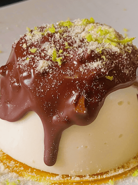 Panna cotta su gelatina gialla e sopra colata cioccolato su piatto bianco