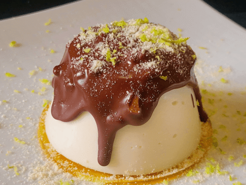 Panna cotta su gelatina gialla e sopra colata cioccolato su piatto bianco