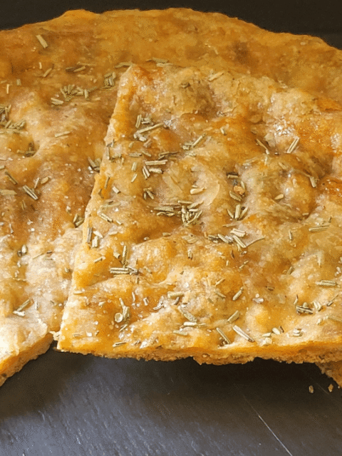 Pizza croccante con rosmarino su piatto ardesia nero