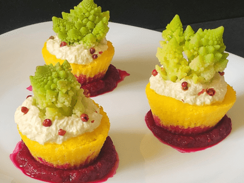 NIDI DI POLENTA GIALLA CON RICOTTA E CAVOLO ROMANESCO SU SALSA ROSSA BARBABIETOLA SU PIATTO BIANCO