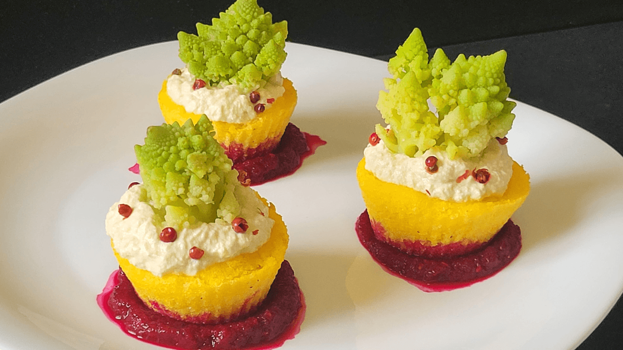 NIDI DI POLENTA GIALLA CON RICOTTA E CAVOLO ROMANESCO SU SALSA ROSSA BARBABIETOLA SU PIATTO BIANCO