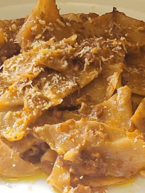 Maltagliati al vino con ragù su piatto bianco