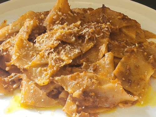 Maltagliati al vino con ragù su piatto bianco