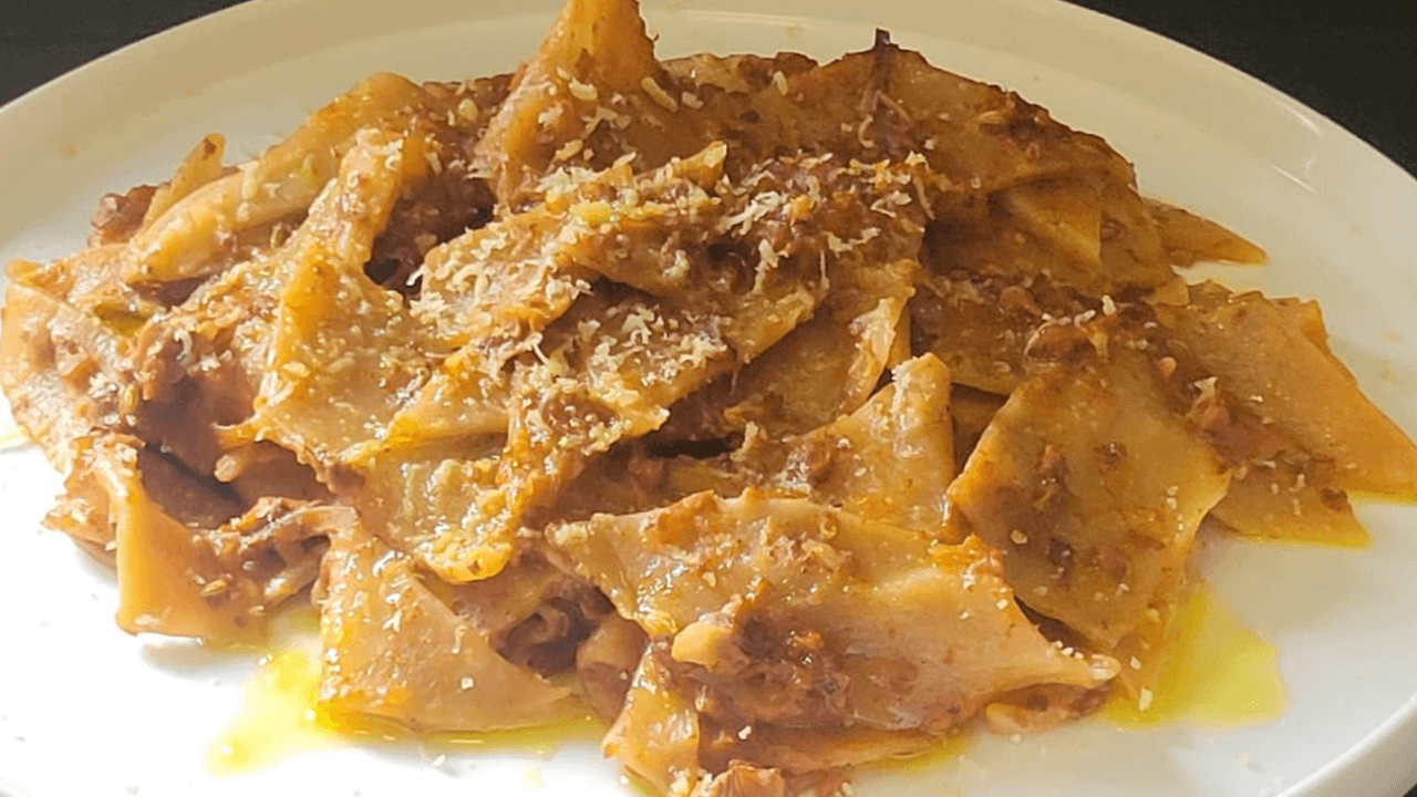 Maltagliati al vino con ragù su piatto bianco