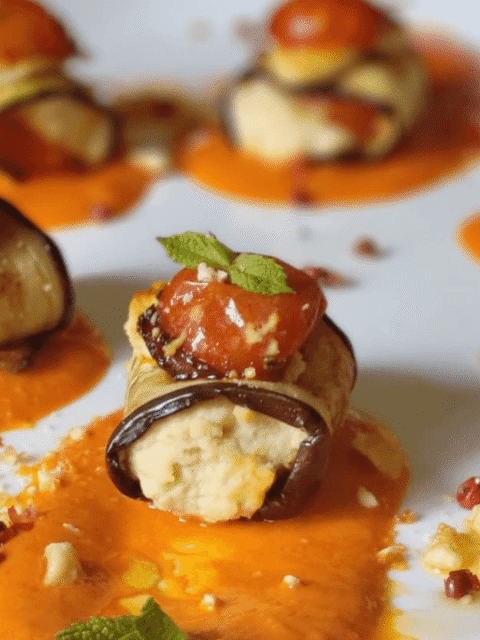 Involtini di melanzane con hummus, pomodorini su crema di peperoni, granella nocciole ,menta su piatto bianco