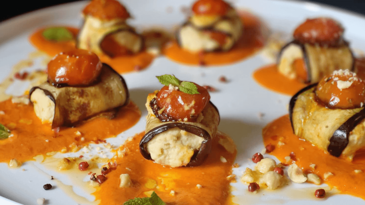 Involtini di melanzane con hummus, pomodorini su crema di peperoni, granella nocciole ,menta su piatto bianco