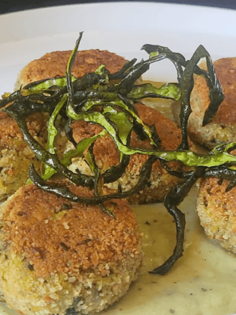 Polpette fritte su piatto bianco e chips di zucchine