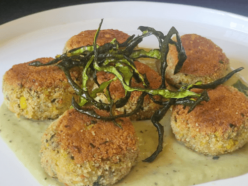 Polpette fritte su piatto bianco e chips di zucchine