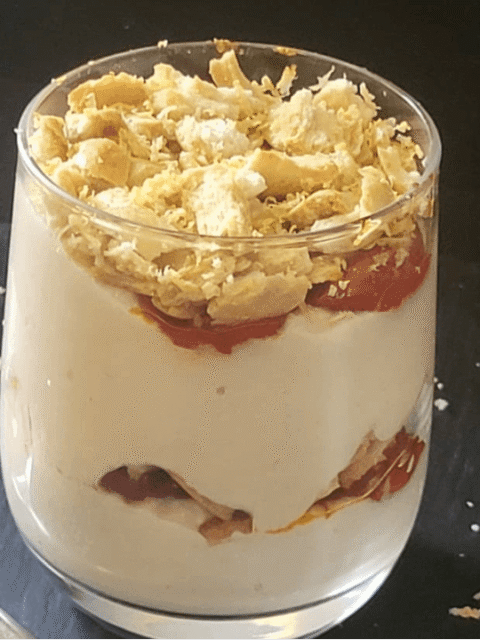 Cheesecake in bicchiere salata a stati su piatto ardesia nero e cucchiaio a cuore