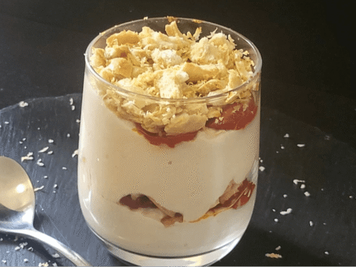 Cheesecake in bicchiere salata a stati su piatto ardesia nero e cucchiaio a cuore