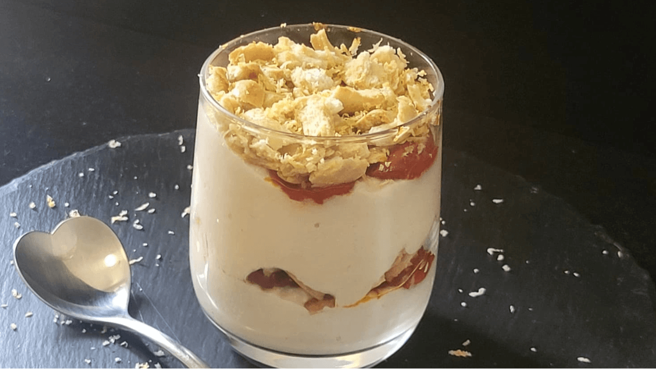 Cheesecake in bicchiere salata a stati su piatto ardesia nero e cucchiaio a cuore