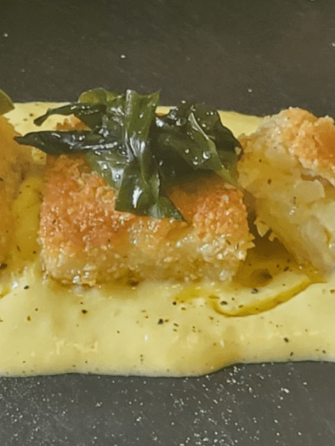 Tomini frutti su una maionese gialla e sopra ciuffi di alghe su piatto ardesia nera