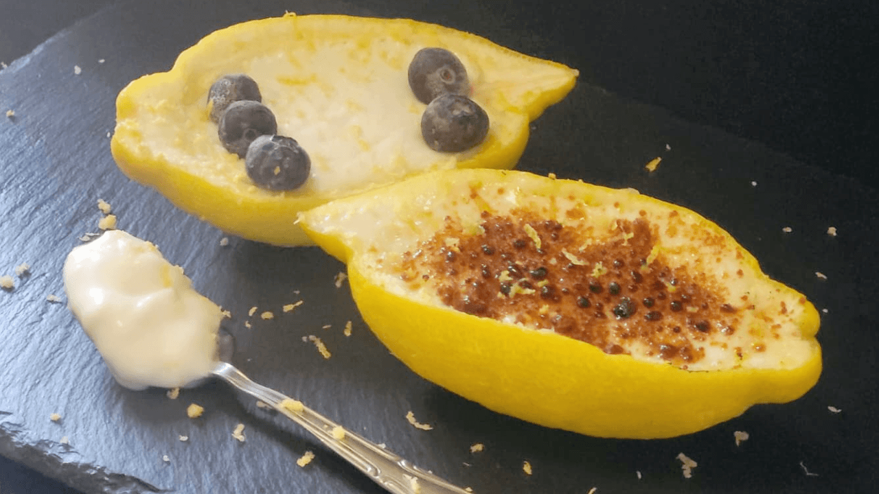 Dessert bianco dentro scorza limone su piatto ardesia nero