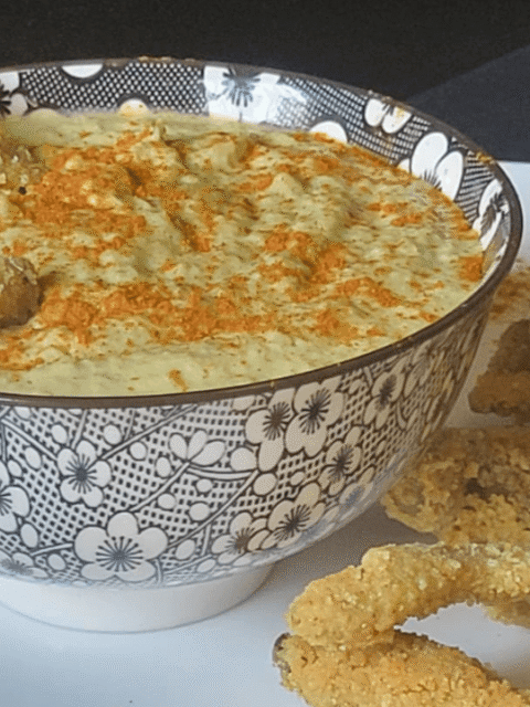Ciotola nera e bianca con hummus di fave verdi e paprika con baccelli croccanti
