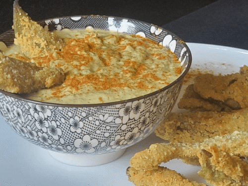 Ciotola nera e bianca con hummus di fave verdi e paprika con baccelli croccanti