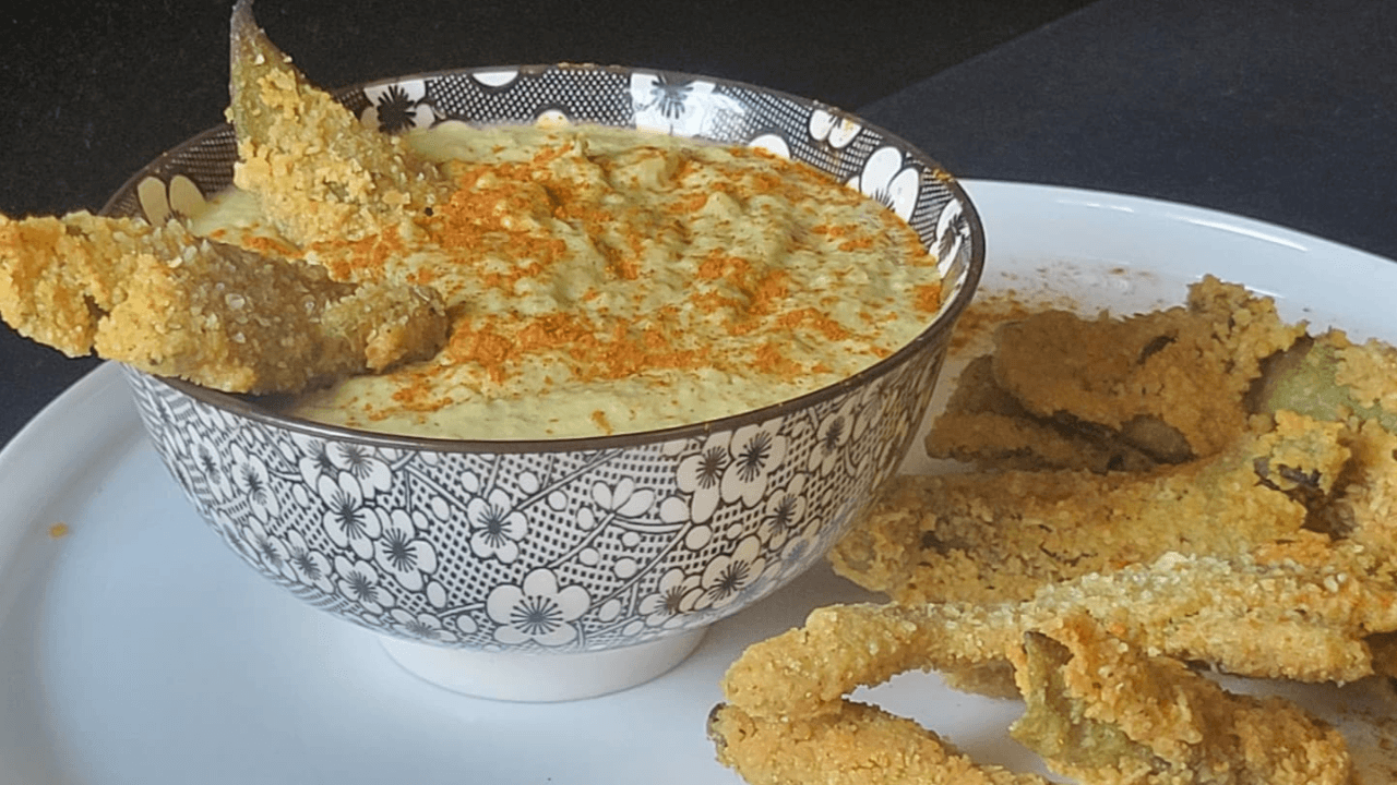 Ciotola nera e bianca con hummus di fave verdi e paprika con baccelli croccanti