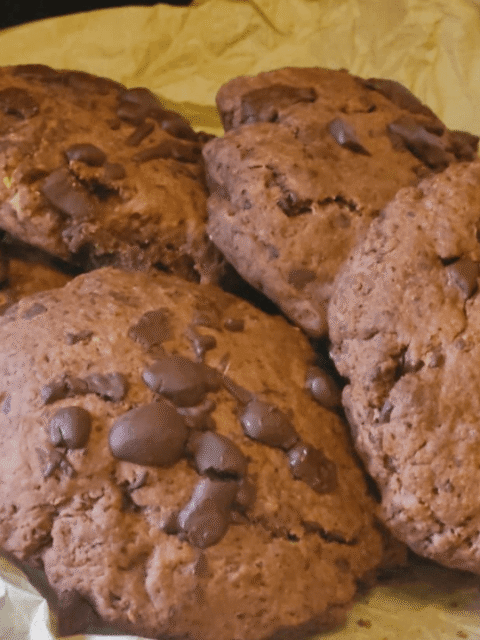 Cookies al cioccolato su carta forno e piatto ardesia nera