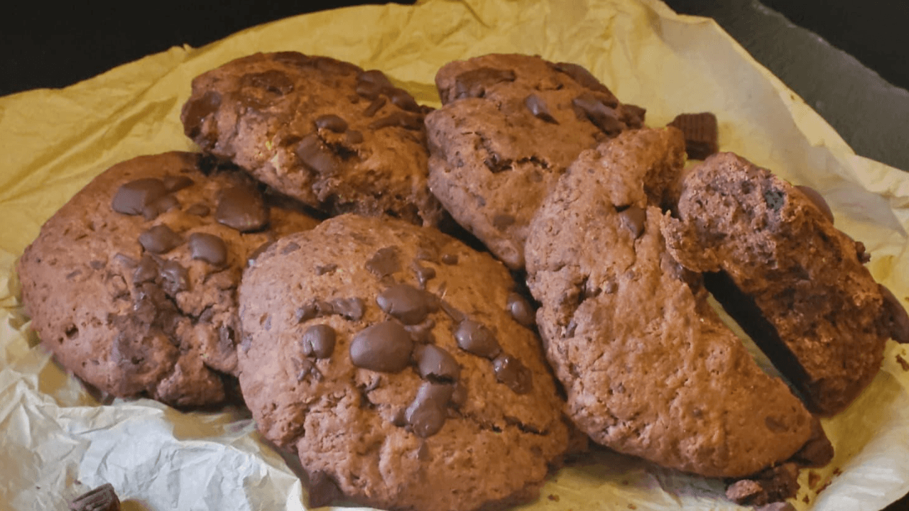 Cookies al cioccolato su carta forno e piatto ardesia nera