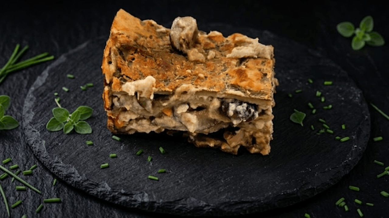 Lasagna con funghi su piatto ardesia nero