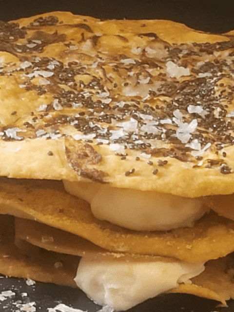 Focaccia a strati di pane lavash con spalmabile e affettato vegano gusto prosciutto su piatto ardesia nero