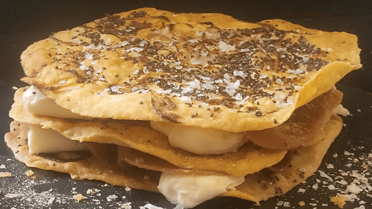 Focaccia a strati di pane lavash con spalmabile e affettato vegano gusto prosciutto su piatto ardesia nero