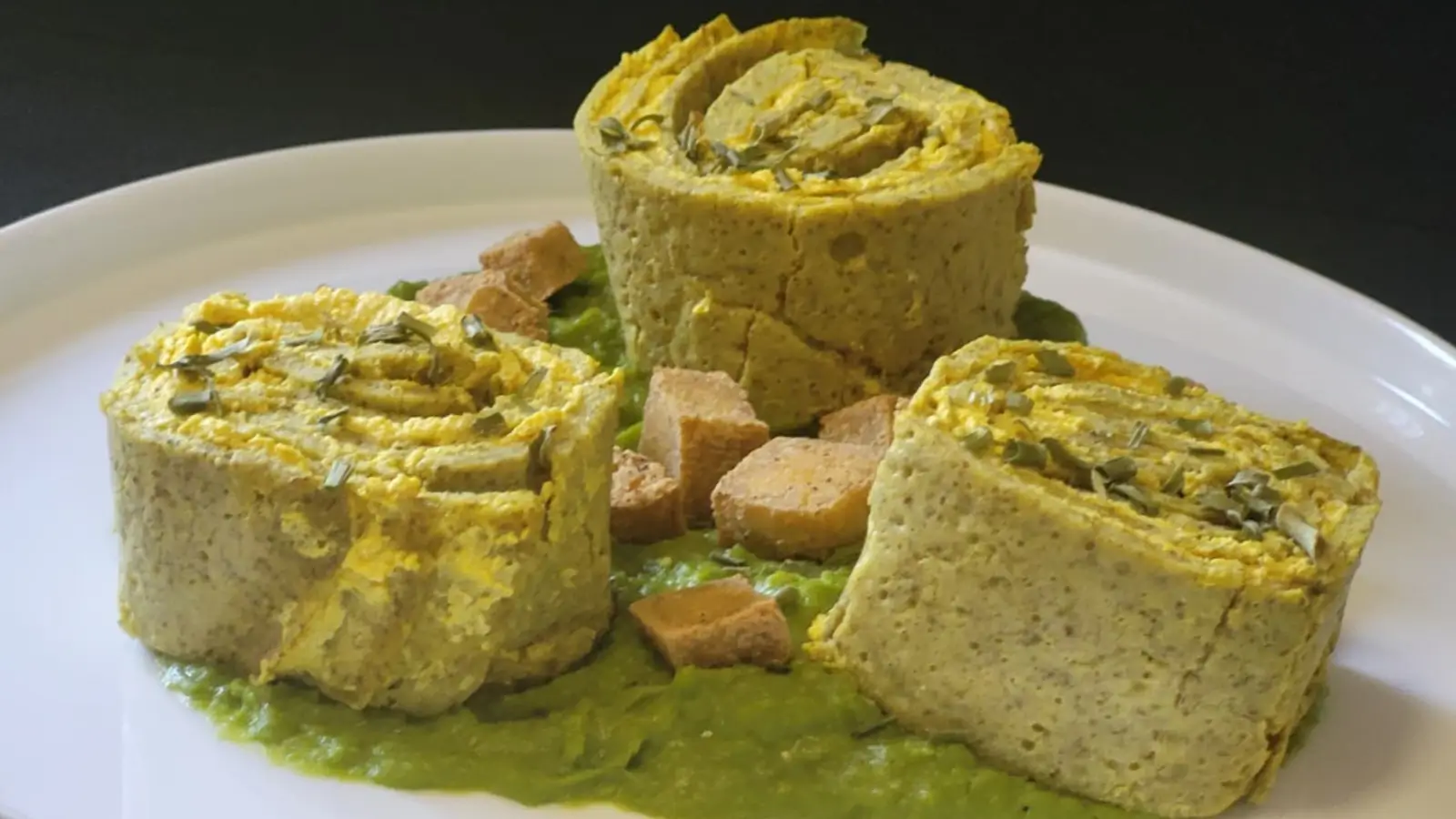 Rotolini di crespelle con ricotta vegetale alla curcuma su crema di piselli e tofu croccante