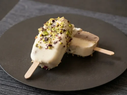 Stecco vegan di semifreddo caffè e mandorla,ricoperto da cioccolato bianco spalmabile al rum su piatto acciaio nero