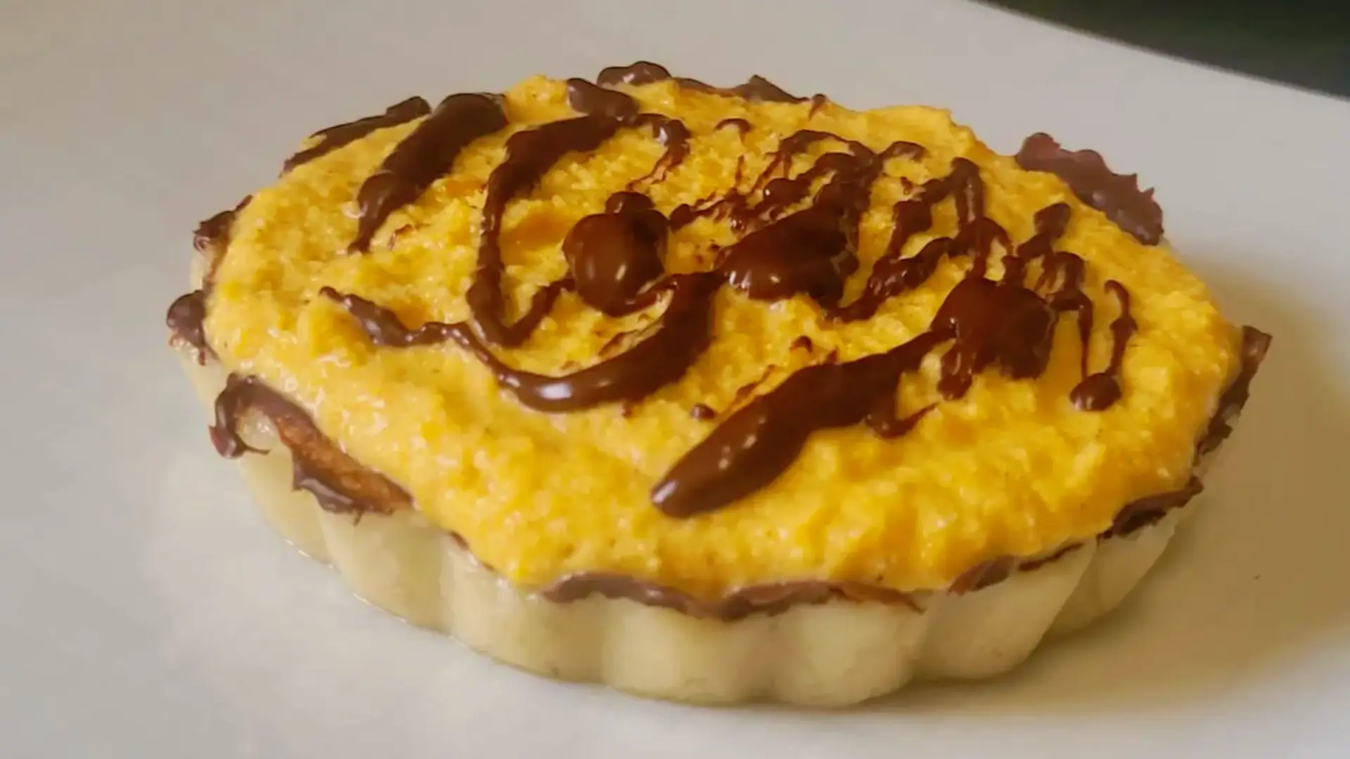 Crostatina crudista zucca e cioccolato su piatto bianco