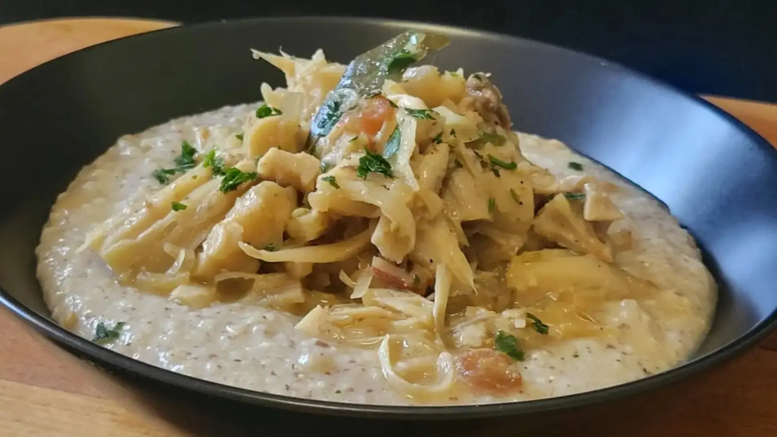 Piatto nero La Copadia del Viandante:lo spezzatino medievale vegano su polenta d’orzo su tagliere legno